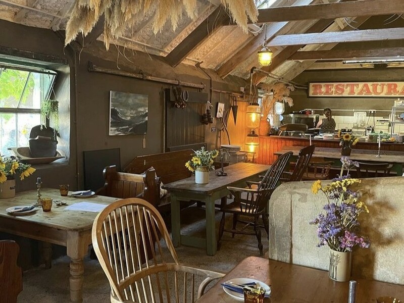 Paternoster Farm, Hundleton, Pembrokeshire, Wales — rustic dining room with wooden beams, mismatched furniture, dried flowers and open kitchen — Wales regional winner, Best Local Restaurant 2025 in The Good Food Guide.